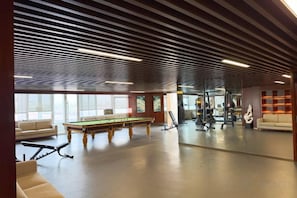 A spacious indoor area with a pool table, seating, and exercise equipment. - Feng Du Hotel (Dezhou)