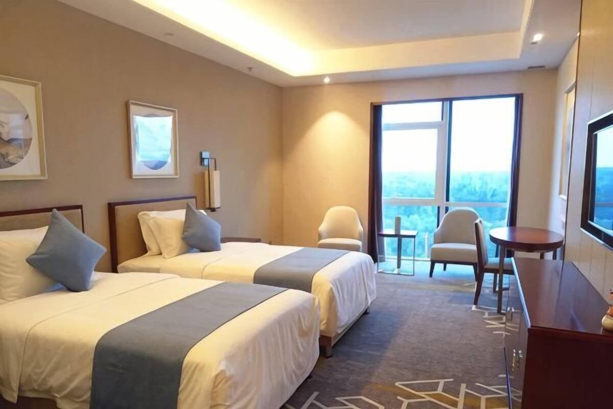 Une chambre d’hôtel avec deux lits, une chaise, un téléviseur et un balcon avec vue.