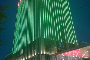 A tall building with vertical lines of illumination. - Feng Du Hotel (Dezhou)