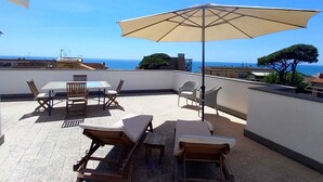 A rooftop terrace with a table and chairs, a lounge chair, and an umbrella. - Sea view penthouse for 2-4 people, large equipped terrace (anzio)