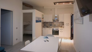 A compact kitchen with white cabinets, a tiled backsplash, and a built-in oven. - Apartment for family with children, 200 mt from the sea (anzio)
