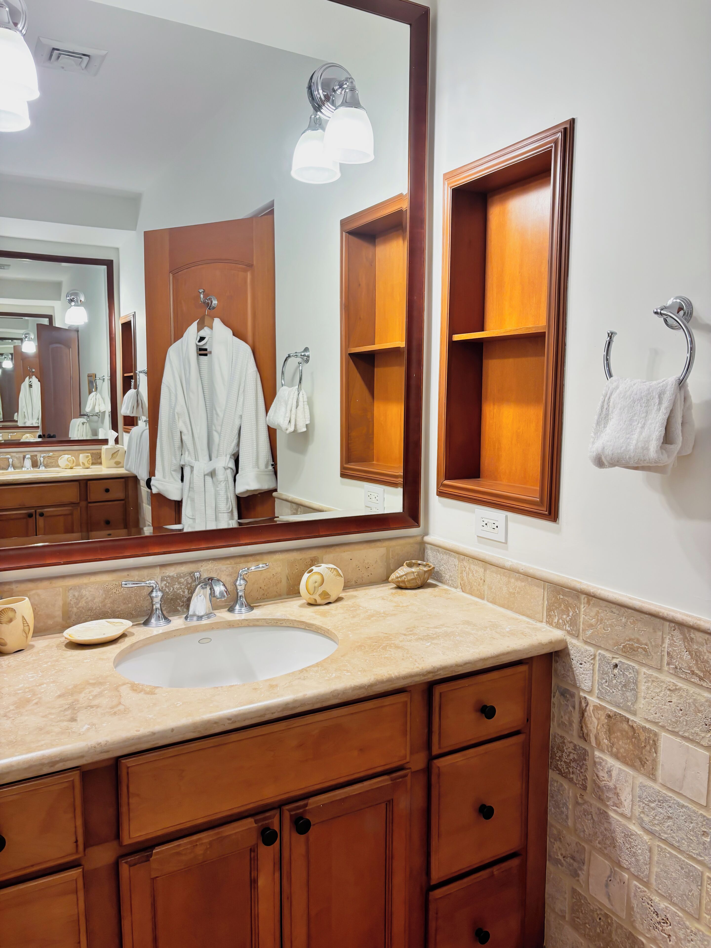 A bathroom with a large mirror, wooden cabinets, a sink, and a towel rack.