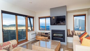 Una sala de estar moderna con ventanas amplias, chimenea y televisor.