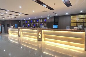 Ein Hotel-Empfangsbereich mit modernem Design, inklusive einer Rezeption, einer Sitzgruppe und einer Wand mit gerahmten Zertifikaten.