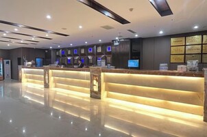 Zona de recepción de un hotel con diseño moderno, que incluye un mostrador de recepción, área de descanso y una pared con diplomas enmarcados.