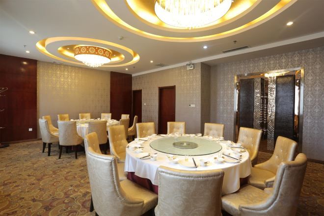 Une salle de conférence avec une table ronde, des chaises et un lustre.
