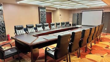 A conference room with a long table and chairs, a projector screen, and a carpeted floor.