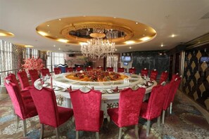 A round dining table with red chairs, a chandelier, and a decorative centerpiece.