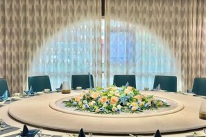 A conference room with a round table, chairs, and a floral centerpiece.