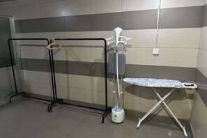 A bathroom with a shower, a hand dryer, and an ironing board.