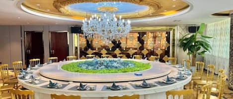 A round dining table with chairs, a chandelier, and a decorative centerpiece.