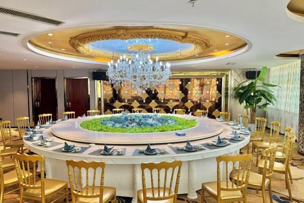 A round dining table with chairs, a chandelier, and a decorative centerpiece.
