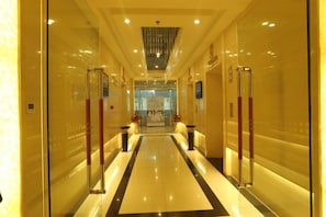 A hotel corridor with glass doors, a central light fixture, and a polished floor. - Rongda International Hotel (Yulin)