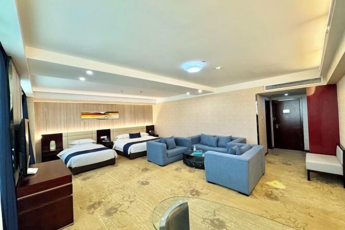 Ein Hotelzimmer mit einem großen Bett, einer Couch, einem Fernseher und einem Schreibtisch.