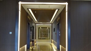 A modern hotel corridor with a polished floor, a central decorative element, and a symmetrical design. - Rongda International Hotel (Yulin)