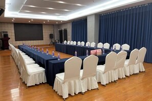 A conference room with a long table, white chairs, and a screen at the front. - Rongda International Hotel (Yulin)