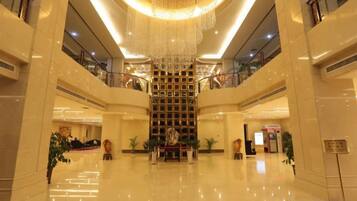 Um hall espaçoso com escadaria central, pisos lustrosos e um candelabro.