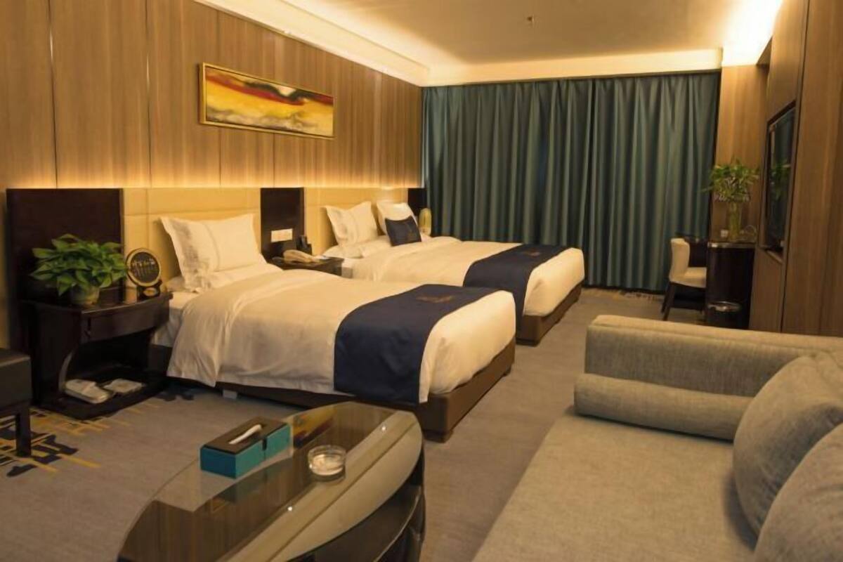 Une chambre d’hôtel avec deux lits, un canapé, un bureau et un tableau au mur.