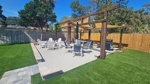 Un patio trasero con muebles de exterior y una pérgola.