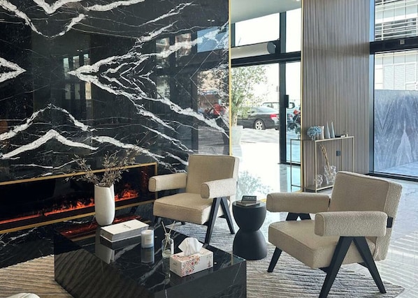 A modern lobby with a black marble fireplace, comfortable seating, and a view of the street.