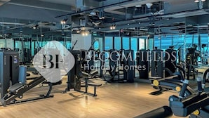 A gym with various exercise equipment, large mirrors, and a wooden floor.
