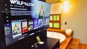 Une salle de bain moderne avec un grand téléviseur à écran plat fixé au mur, diffusant un film.