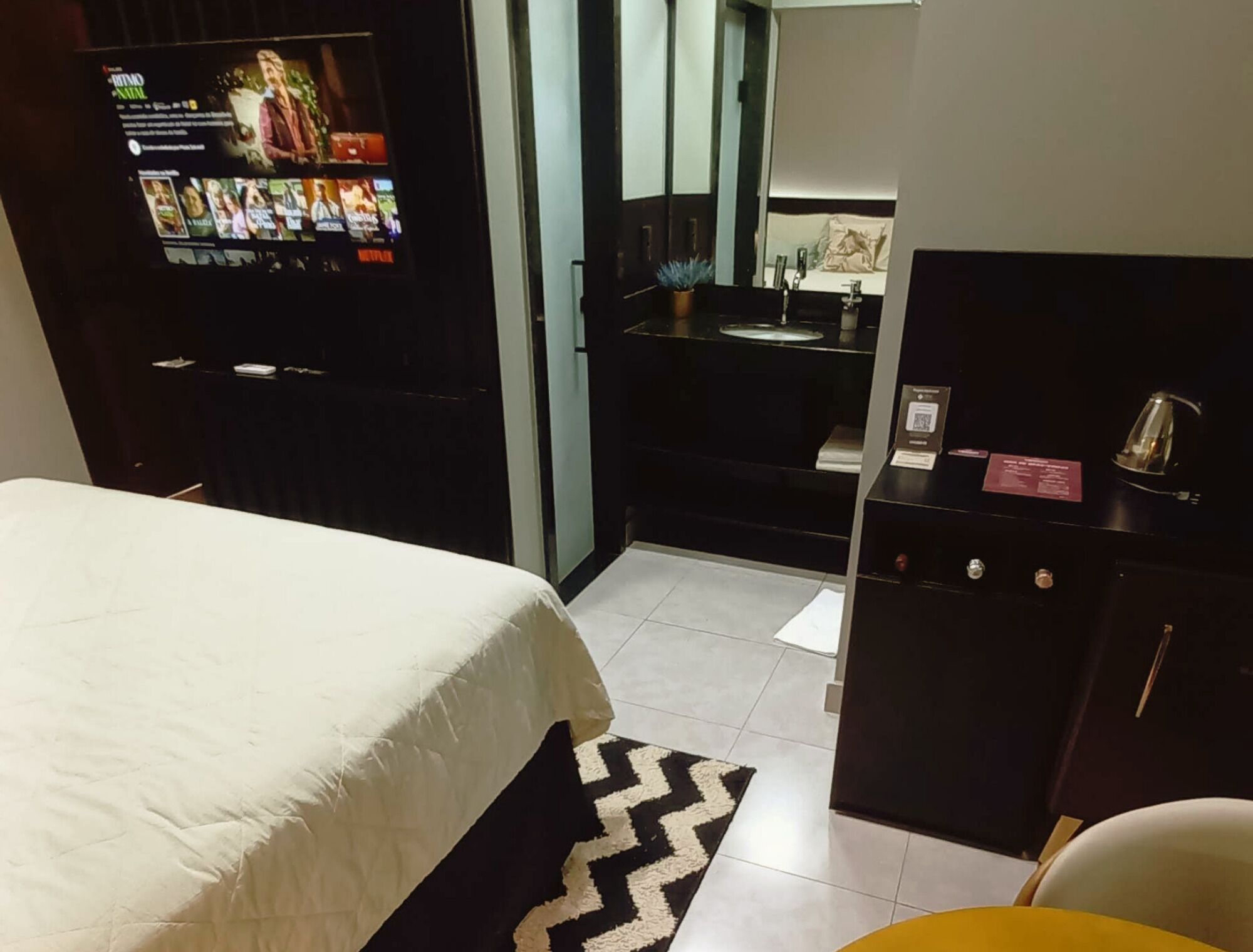 Une chambre d’hôtel équipée d’un lit, d’un téléviseur proposant une sélection de films, d’un lavabo et d’un miroir.