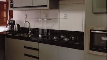A kitchen with a black countertop, stainless steel appliances, and white cabinets.