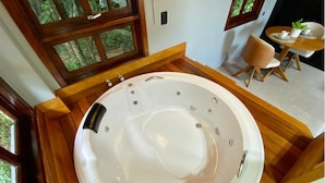 Un bain à remous dans une pièce dotée d’un plancher en bois et de grandes fenêtres.