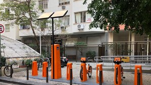 A street with orange bollards, a parked bicycle, and a building with a sign.