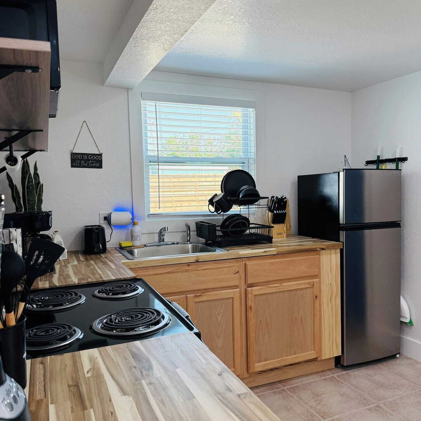 Una cocina moderna con encimera de madera, electrodomésticos de acero inoxidable y una ventana con persianas.