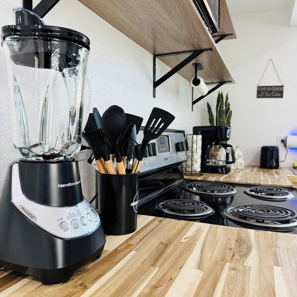 A kitchen with a Hamilton Beach blender, a coffee maker, and a stove.