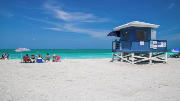 A lifeguard tower on a sandy beach with clear turquoise water.