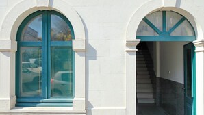 Un bâtiment doté de deux fenêtres en arc de cercle et d’un escalier menant à l’entrée.