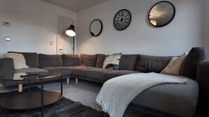 A modern living room with a sectional sofa, a glass coffee table, and decorative mirrors on the wall. - Stylish Stay in Vibrant Salford, Manchester! (Salford)