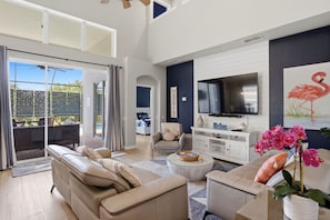 A spacious living room with a sofa, armchairs, a coffee table, and a TV.