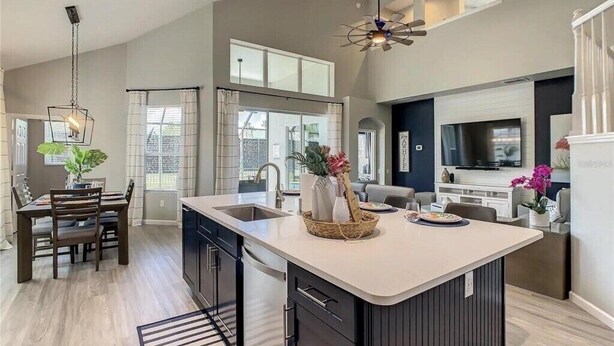 Una cocina moderna con una isla grande, muebles oscuros y una zona de comedor con mesa y sillas.