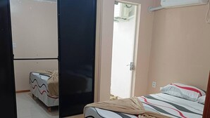 Un dormitorio con cama, armario, espejo y ventilador de techo.