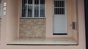 Un edificio de dos pisos con fachada de ladrillo, una puerta blanca y ventanas con rejas.