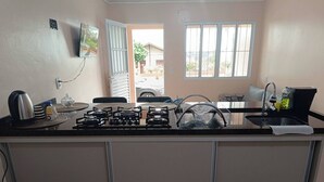 Una cocina con estufa a gas, lavamanos y ventana con vistas al exterior.