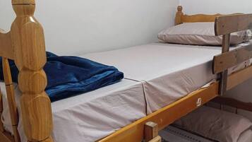 A bunk bed with a wooden frame and a blue blanket on the lower bunk.