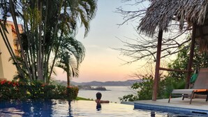 An infinity pool with a view of the sea and mountains at sunset. - Stunning Condo with Panoramic Beach, Ocean, and Mountain Views in Playa Flamingo (Playa Flamingo)