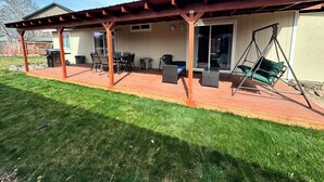 Un patio cubierto con una parrilla, asientos exteriores y una silla colgante.