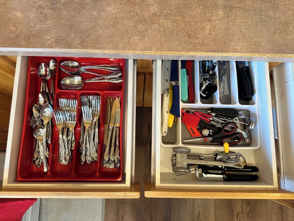 A drawer with compartments containing various utensils and tools.