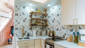 Une cuisine de taille réduite, avec des meubles blancs, un four encastré et un ventilateur de plafond.
