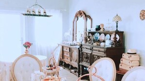 A room with a vintage dresser, a mirror, and a chandelier.