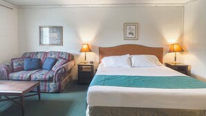 Ett hotellrum med en säng, en soffa, två s ängbord med lampor och ett litet bord.