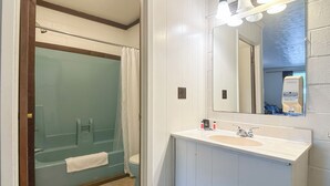 Ett badrum med en dusch som är avskärmad med glasväggar, ett vitt handfat och en spegel ovanför.