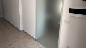 A hallway with a sliding door, a light switch, and a vent on the wall. - Room25 InCentro Guest House (Cercola)