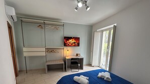 A bedroom with a bed, a desk, a chair, a TV, and a window. - Room25 InCentro Guest House (Cercola)